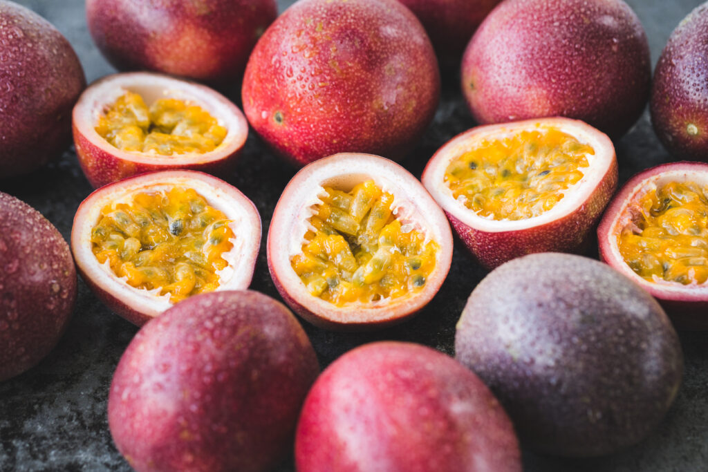 An assortment of Passionfruits, whole and halved. This is the raw material used to produce Passionfruit NFC Juice & Juice Concentrate.