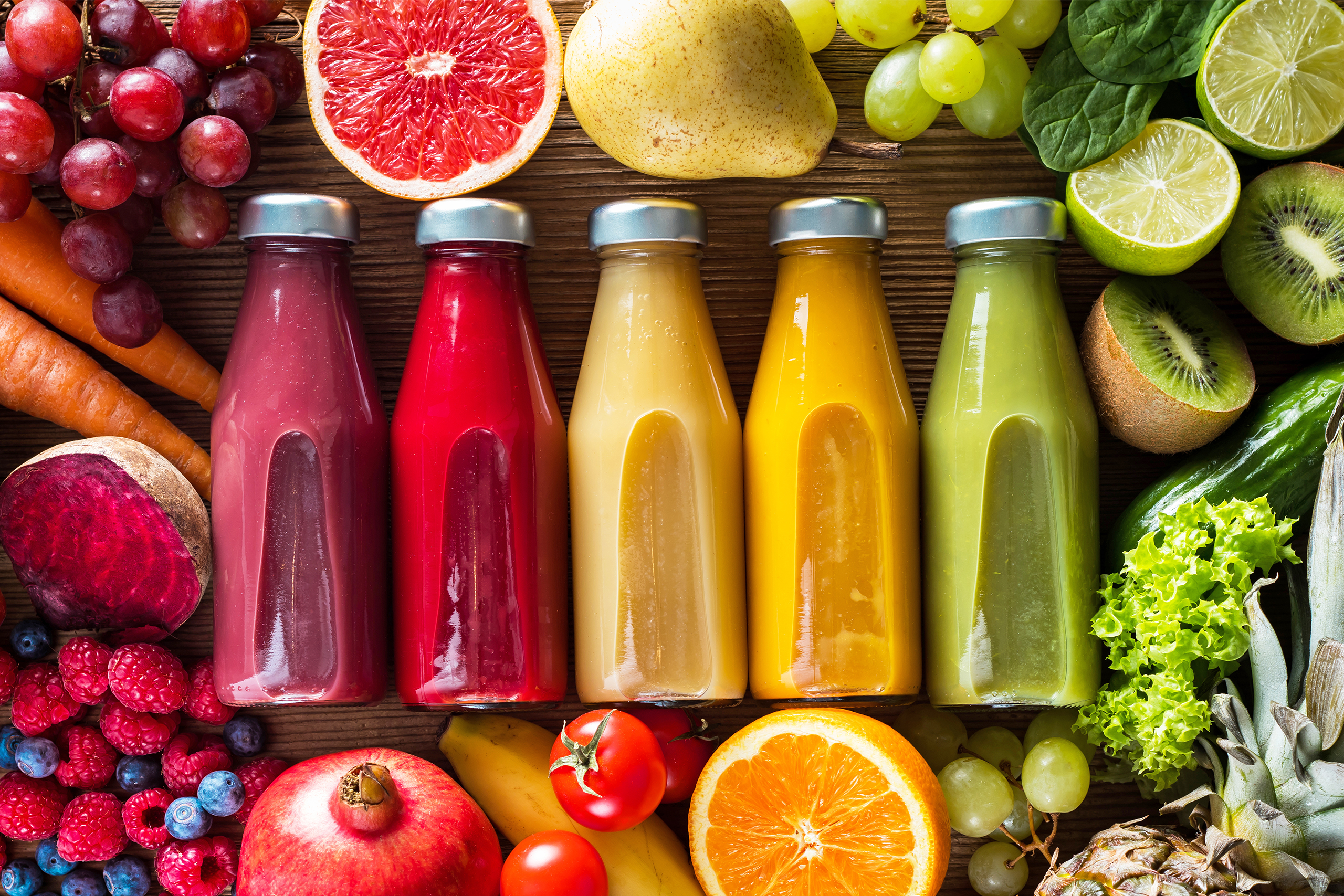 A colorful assortment of bottled juices with an array of fruits surrounding the bottles.