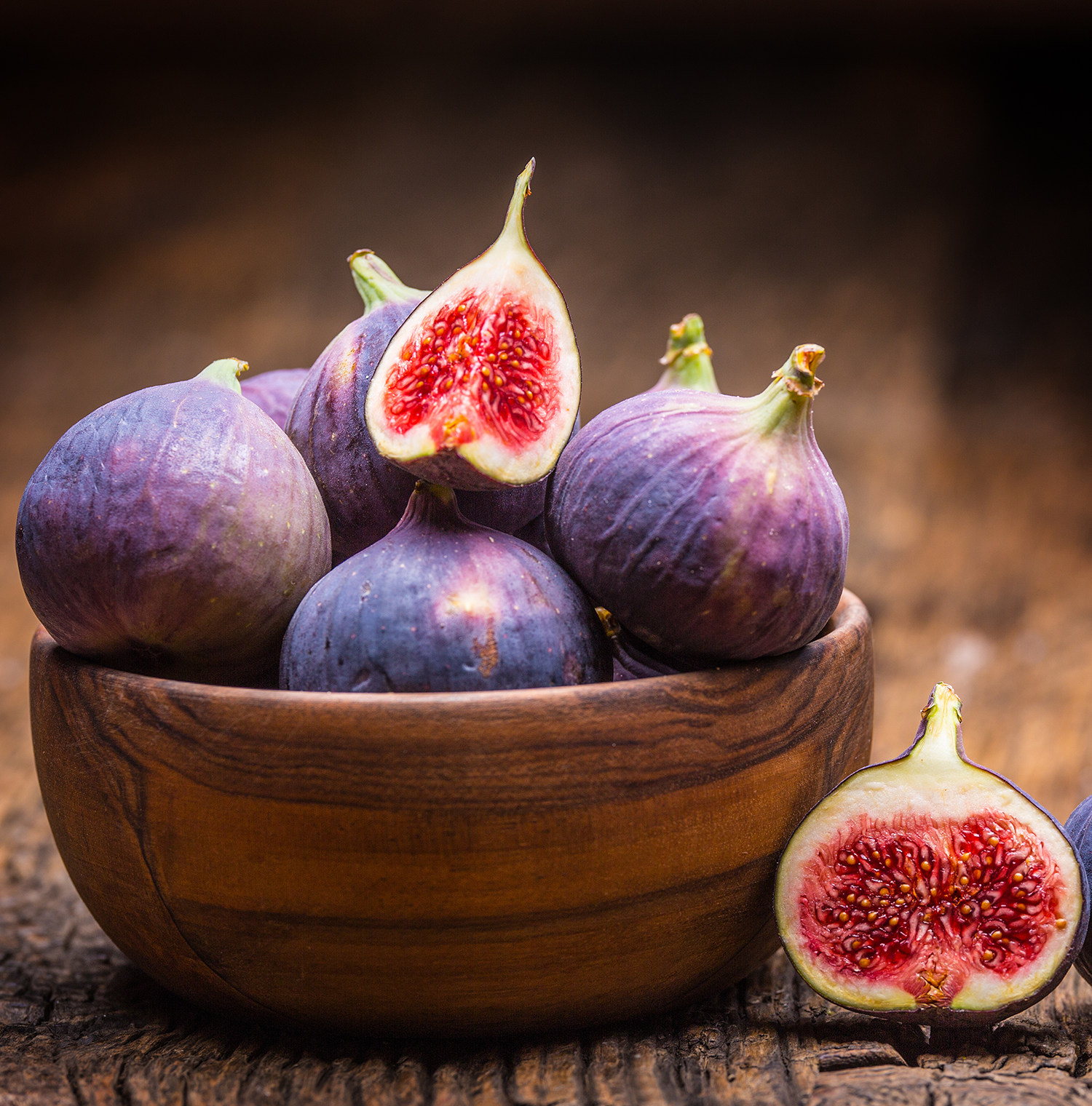 A wooden bowl full of figs.