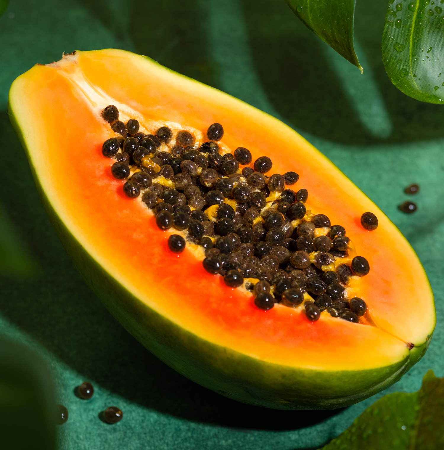 A halved papaya resting on a green surface