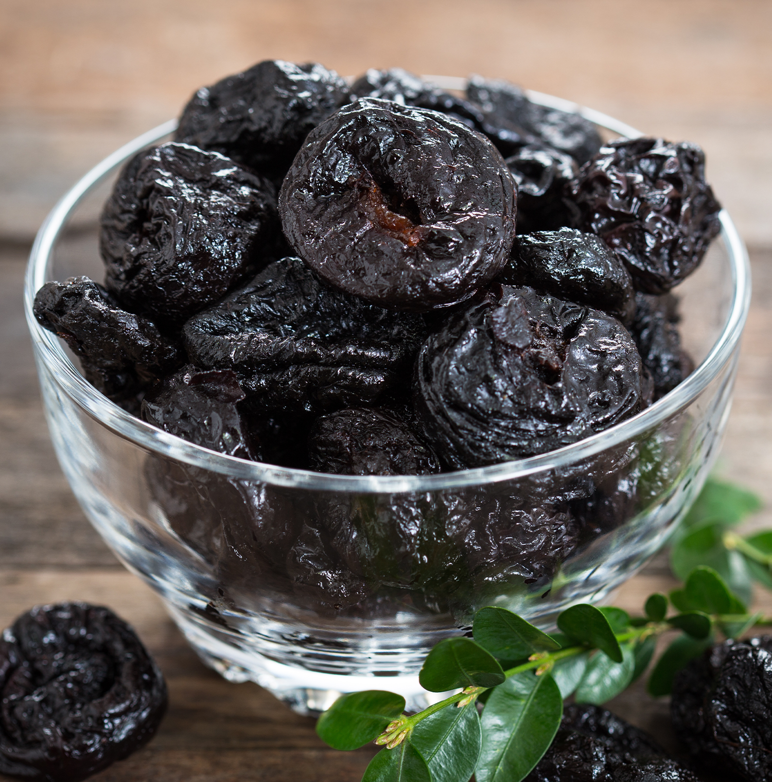 A clear acrylic bowl full of prunes