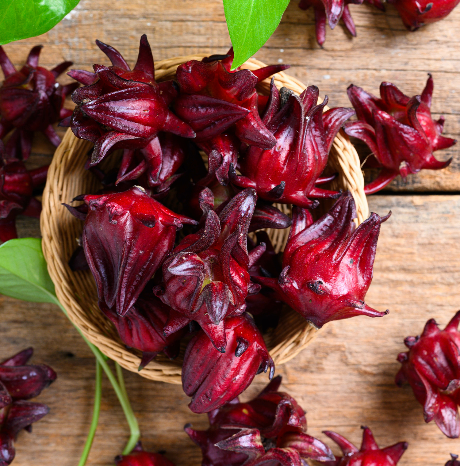 A wooden bowl full of hibiscus, resting on a wooden surface