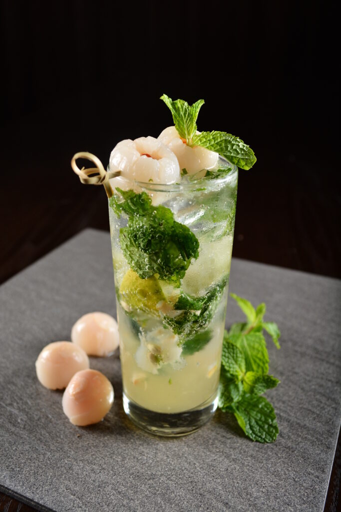 Refreshing lychee mojito cocktail with fresh mint, lime, and whole lychees, highlighting the tropical flavors enhanced by Lychee Puree.